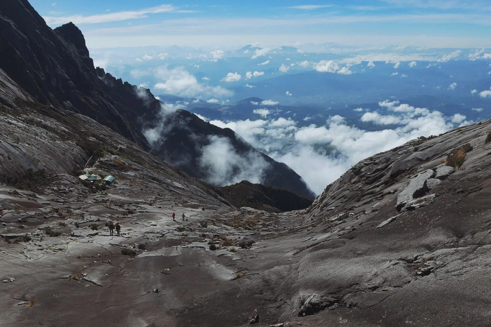 Climbers crossing the granite summit plateau of Mount Kinabalu above the clouds