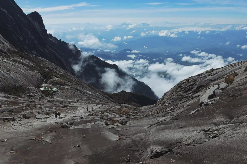 Climbers crossing the granite summit plateau of Mount Kinabalu above the clouds