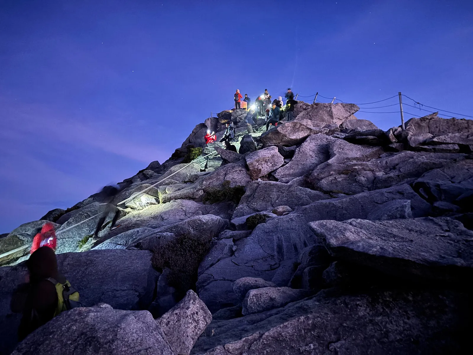 Climbers with headlamps on the final rocks to Low's Peak before dawn