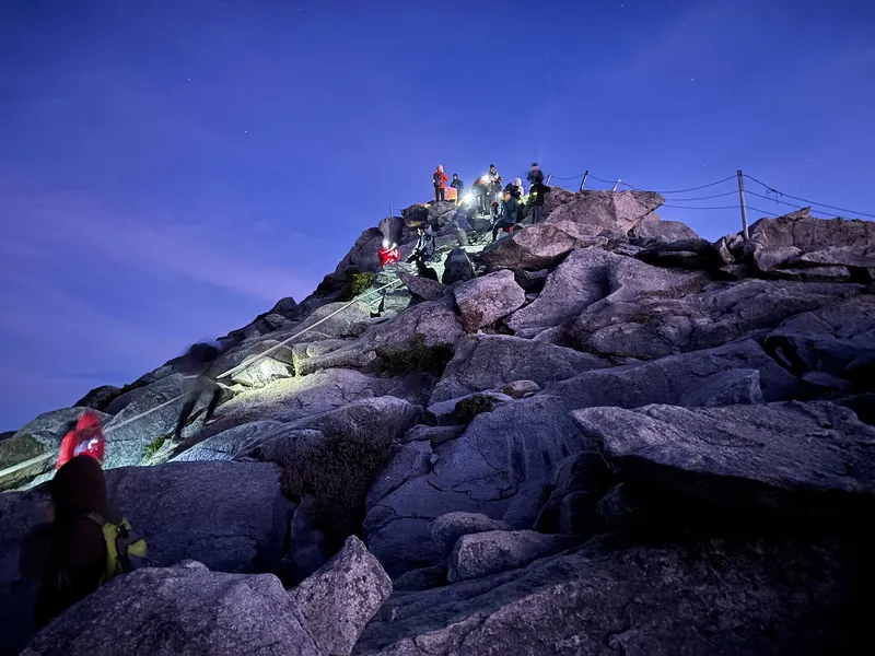 Climbers with headlamps on the final rocks to Low's Peak before dawn