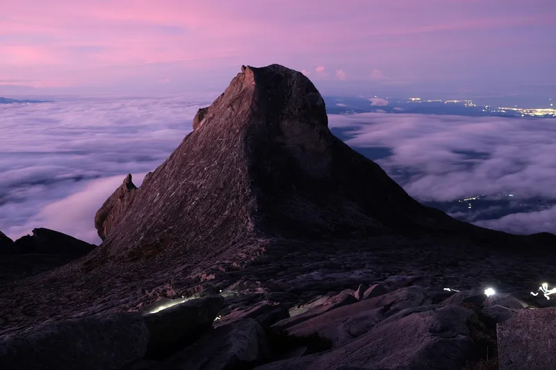 Climbers climbing towards Low's peak just before sunrise. St. John's Peak on the background. Mount Kinabalu, Sabah, Borneo.