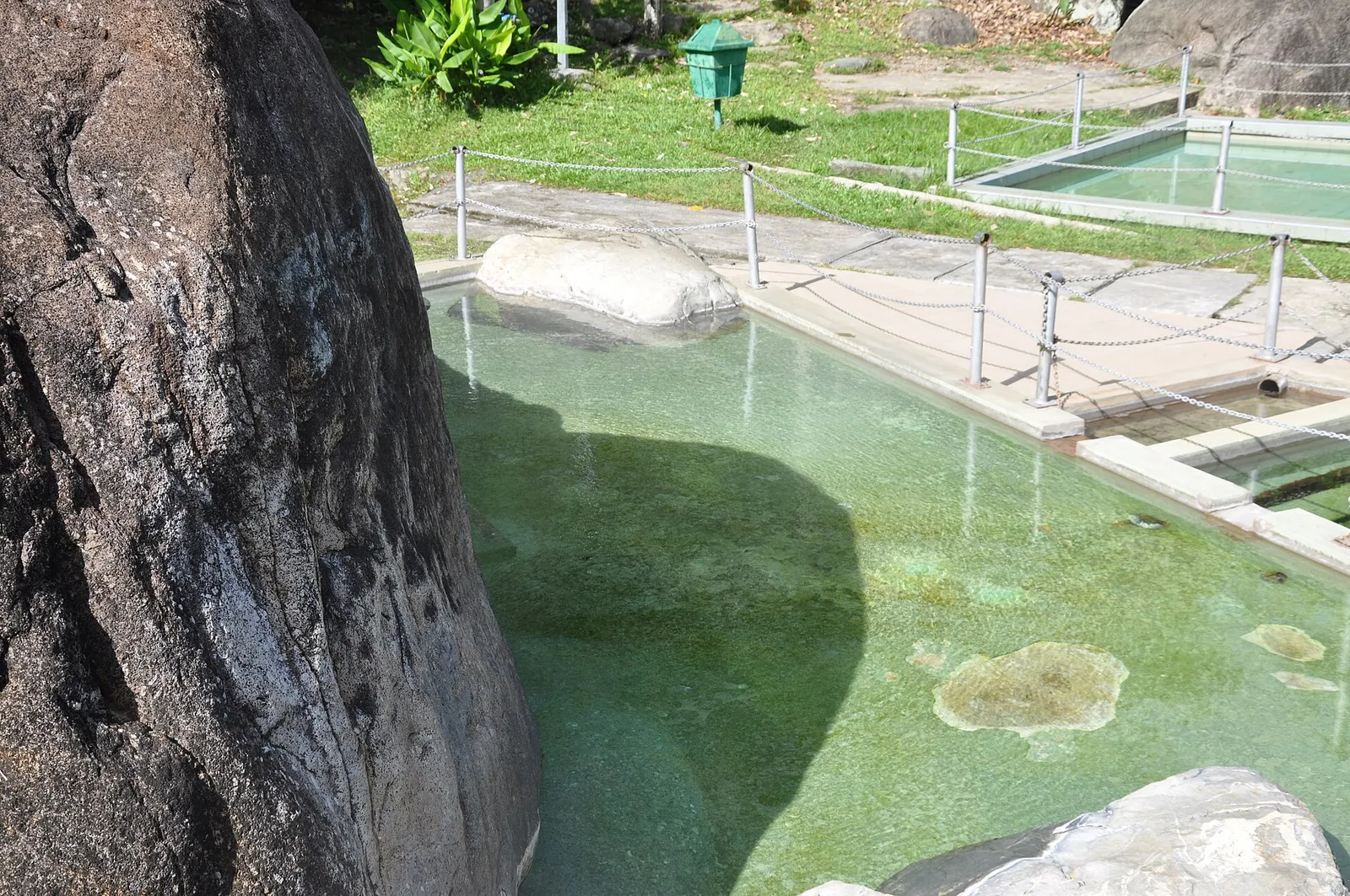 Open-air hot spring pool beside a granite boulder at Poring Hot Springs