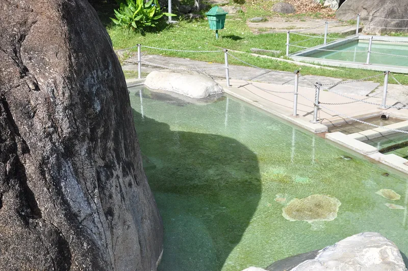 Open-air hot spring pool beside a granite boulder at Poring Hot Springs